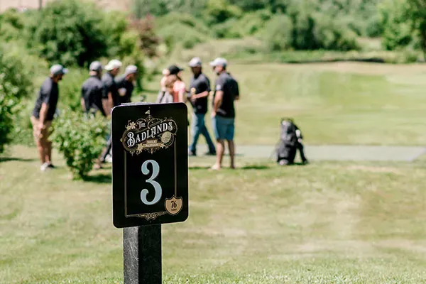 A group of golfers gather to socialize near the third tee box at The Badlands.